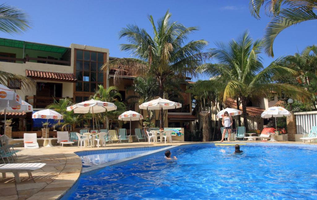 a group of people in a swimming pool with umbrellas at Villa'l Mare Hotel in Maresias