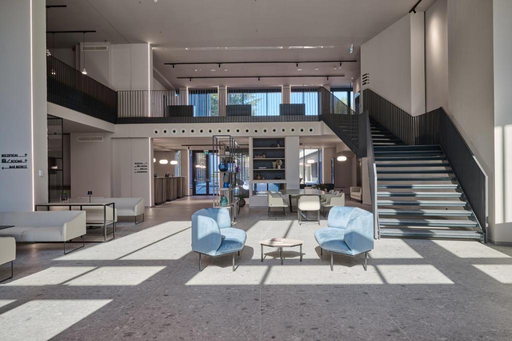 una hall con sedie blu e una scala di RMH Modena Raffaello a Modena