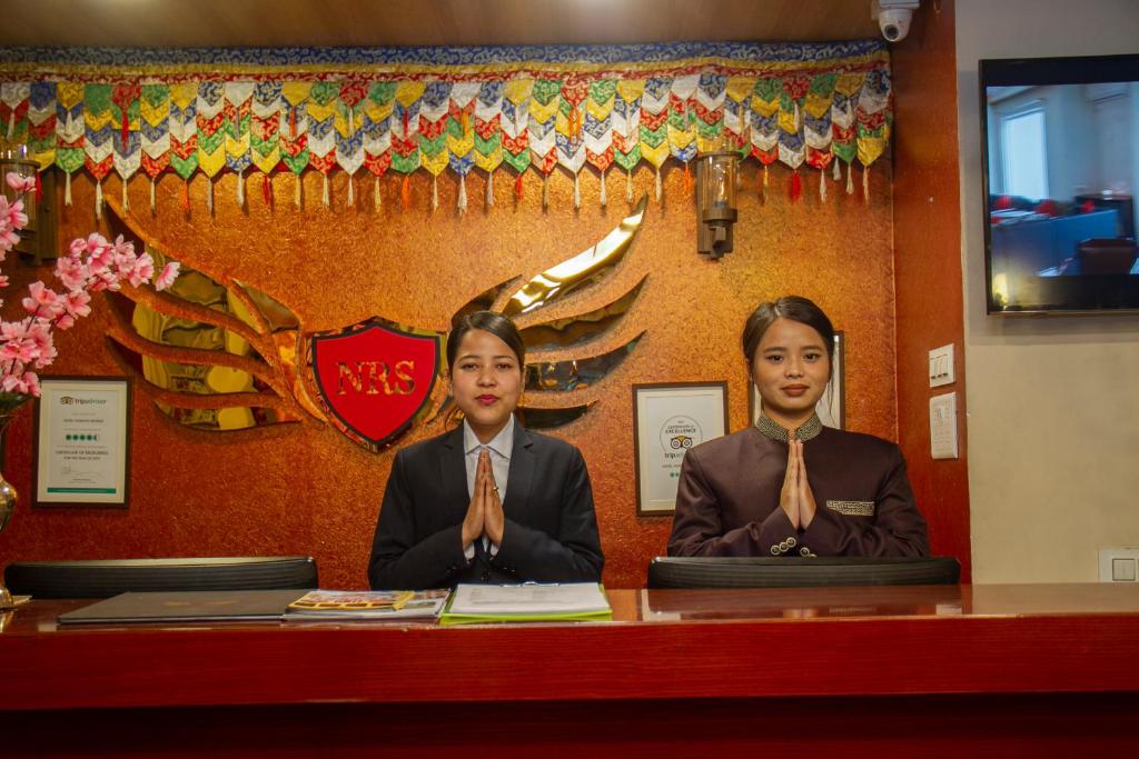 Dos mujeres con corbatas sentadas en un escritorio en NRS Norling Retreat en Darjeeling