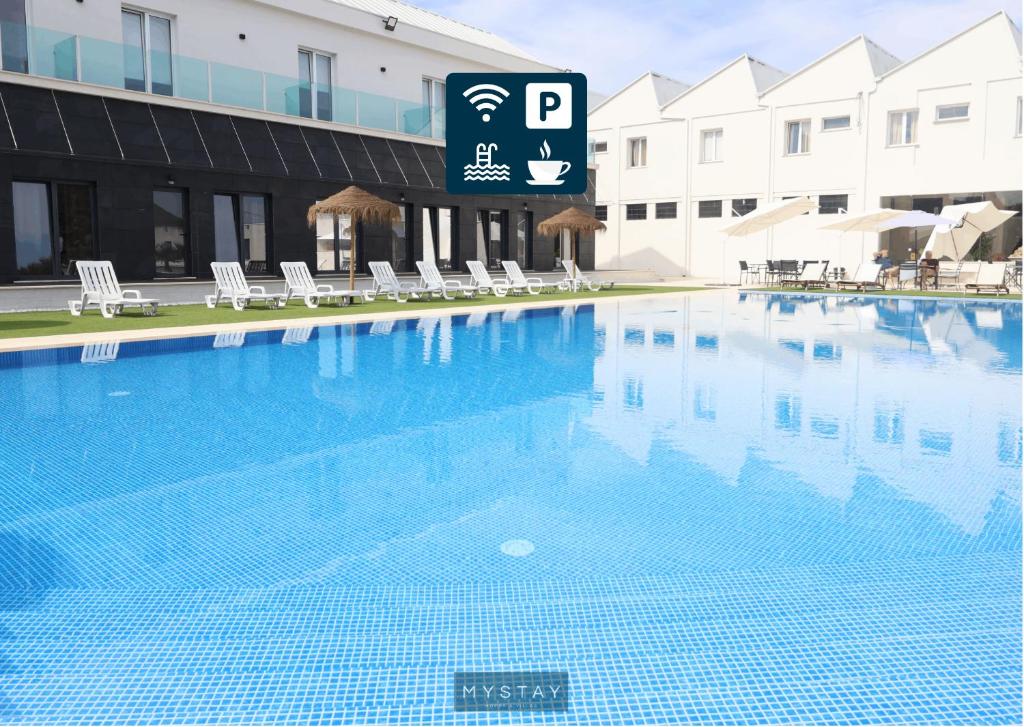 a large blue swimming pool in front of a building at Hotel Lena Village in Mortágua