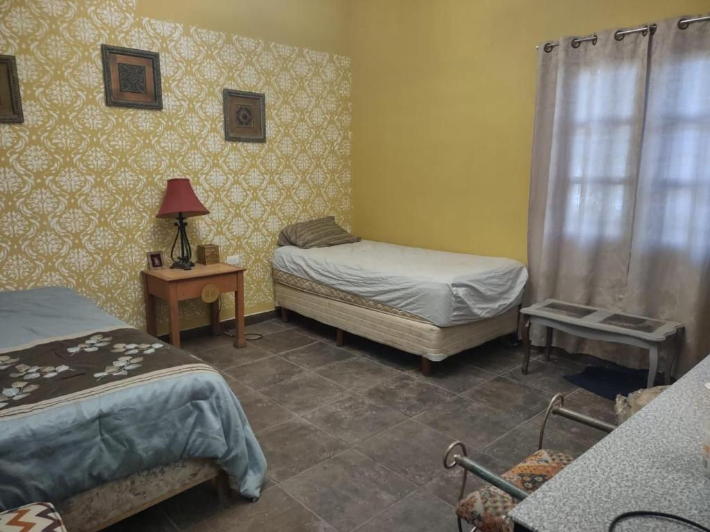 um quarto com 2 camas e uma mesa com um candeeiro em CASA RÚSTICA PARA HOSPEDAJE em El Saucito