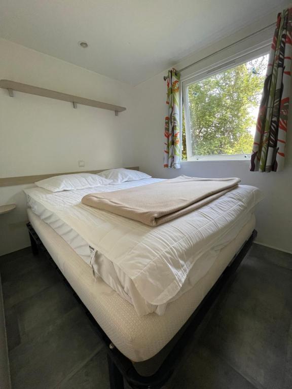 a large bed in a bedroom with a window at Mobilehome climatisé avec TV pour 4 à 6 personnes in Boofzheim