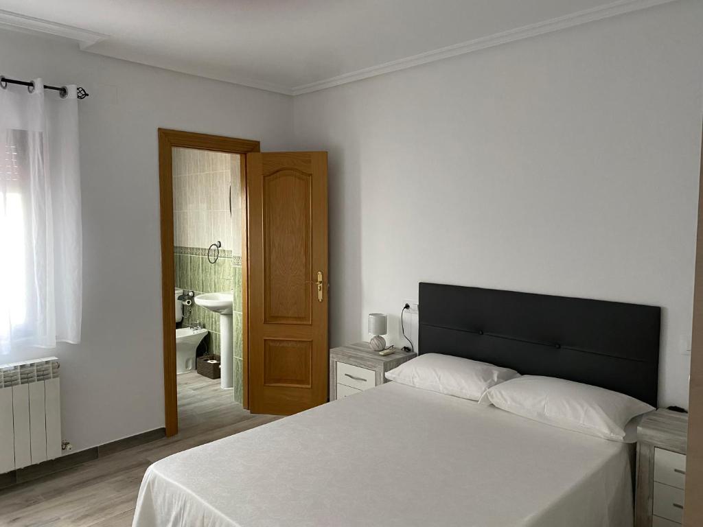 1 Schlafzimmer mit einem weißen Bett und einem Badezimmer in der Unterkunft TRES COLUMNAS in Ciudad-Rodrigo