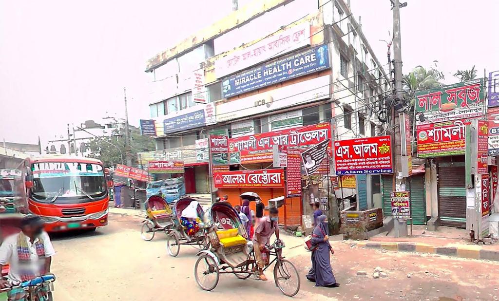 una trafficata strada cittadina con autobus e risciò di Hotel Al-Hayat Abasik a Dhaka
