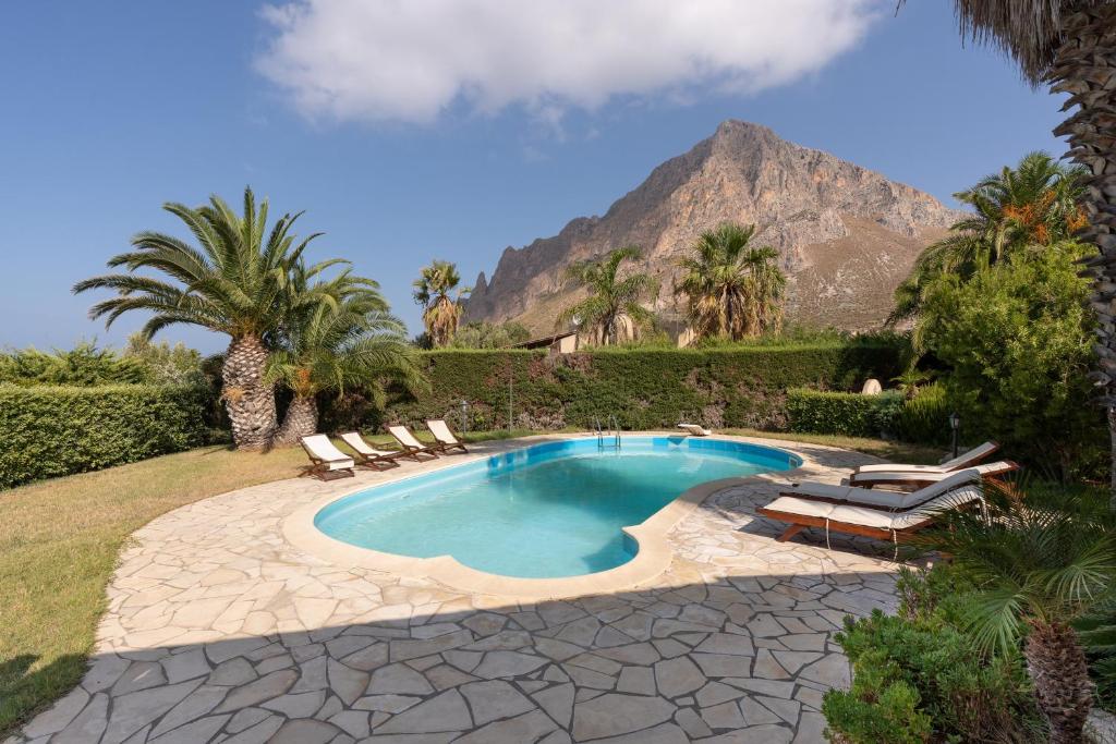 a pool with chairs and a mountain in the background at Amazing sunset with swimming pool in Custonaci
