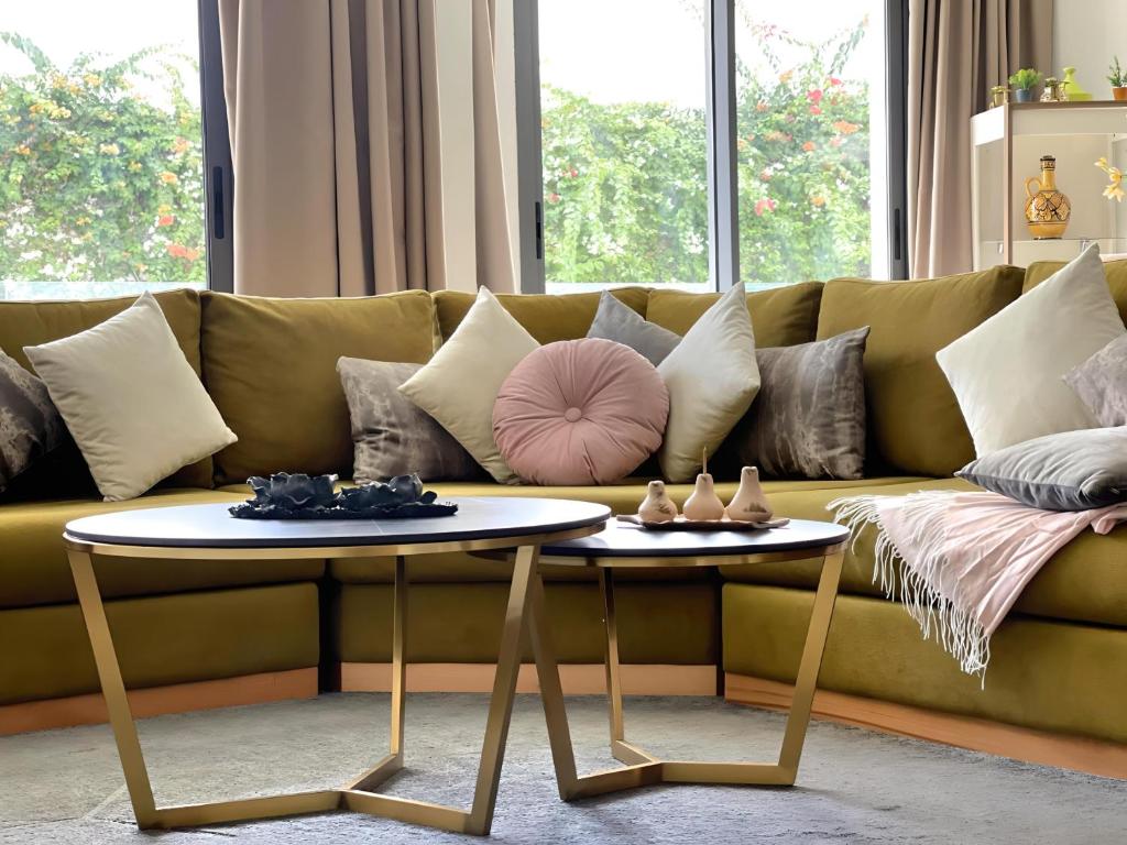 uma sala de estar com um sofá verde com duas mesas em 2 bedrooms with huge terrace access to the pool em Agadir