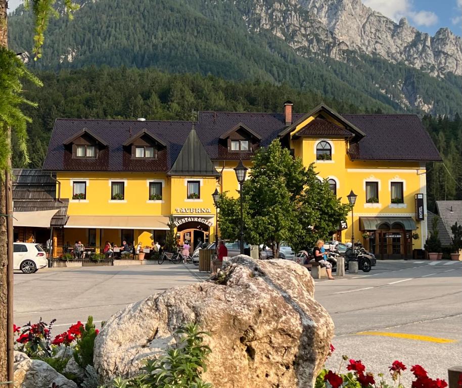 un grand bâtiment jaune dans une ville avec une montagne dans l'établissement Hotel Kotnik Superior, à Kranjska Gora