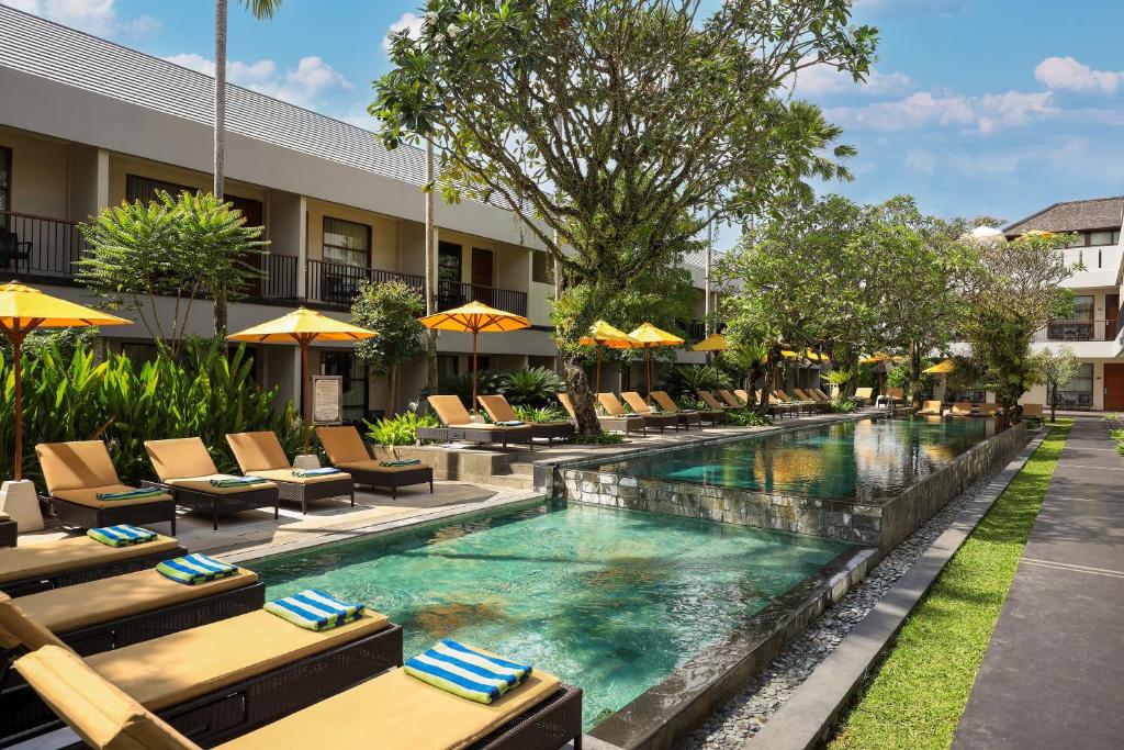 een zwembad in een hotel met stoelen en parasols bij Amadea Resort & Villas Seminyak Bali in Seminyak