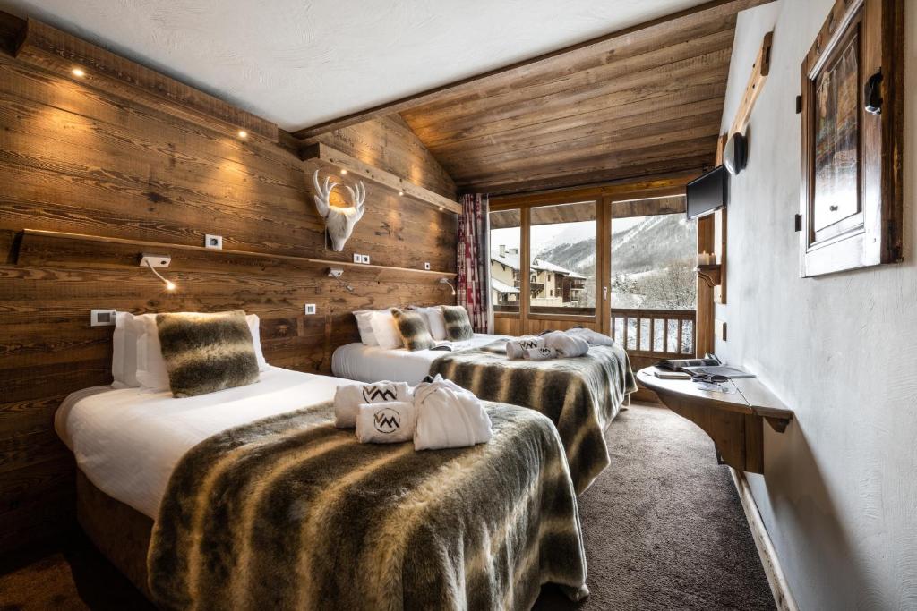 three beds in a room with wooden walls at Hôtel Ski Lodge - Village Montana in Val dʼIsère