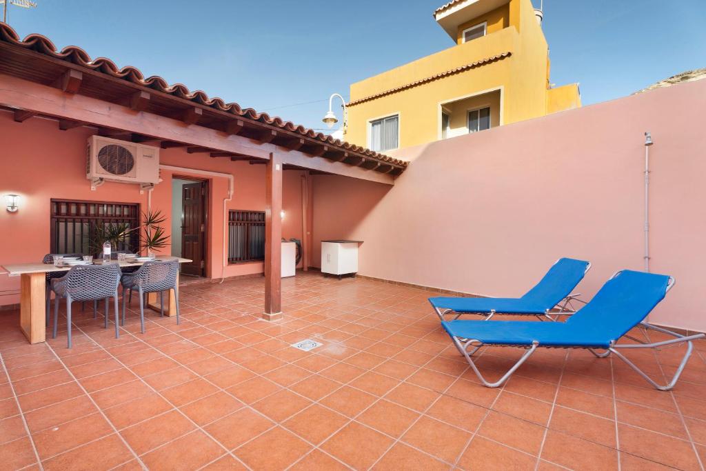 um pátio com cadeiras azuis e uma mesa numa casa em Casa Rural Paula Maretas Beach em Santa Cruz de Tenerife