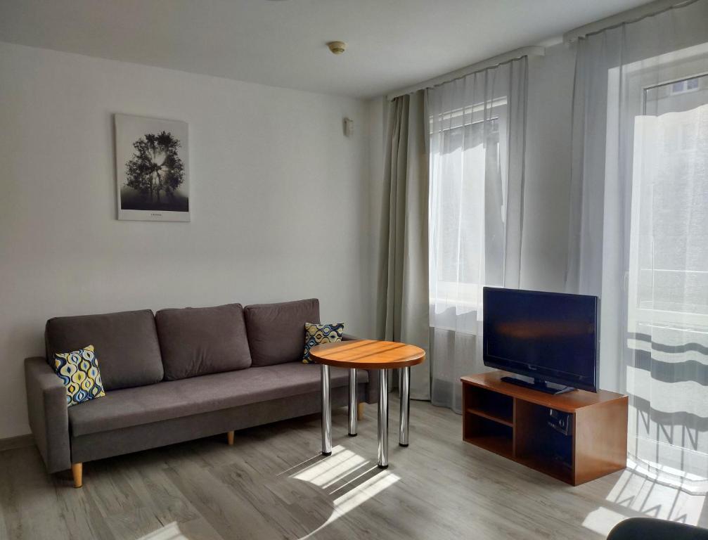 a living room with a couch and a table and a tv at Warsaw Apartments Magnolie in Warsaw