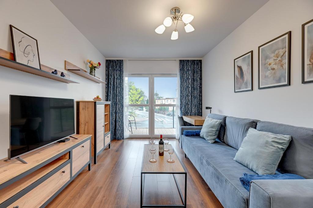 a living room with a blue couch and a tv at Apartment Brzeźno Beach by TriApart in Gdańsk