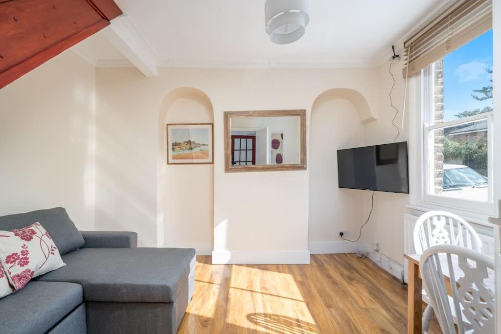 a living room with a couch and a tv at Cottage by Cutty Sark, Greenwich in London