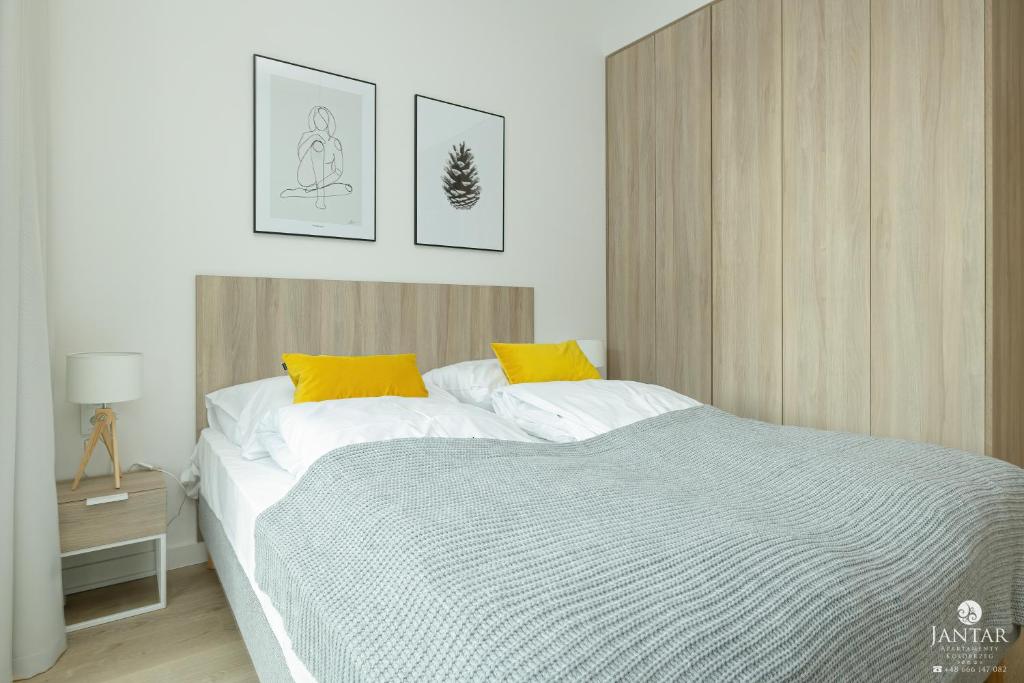 a bedroom with a large bed with yellow pillows at Shellter Apartments 117 K - by Jantar Apartamenty in Rogowo