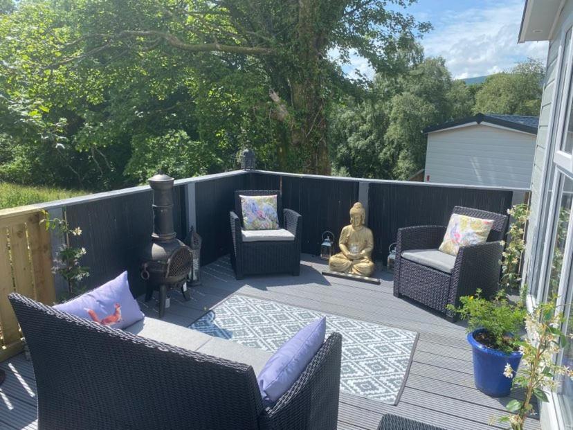 a patio with wicker chairs and a fire place at Lovely new caravan by Loch Long in Cove