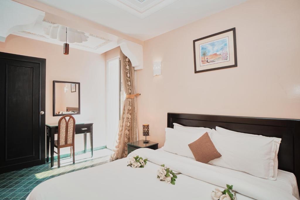 a bedroom with a bed and a desk and a chair at Hôtel Texuda in Rabat