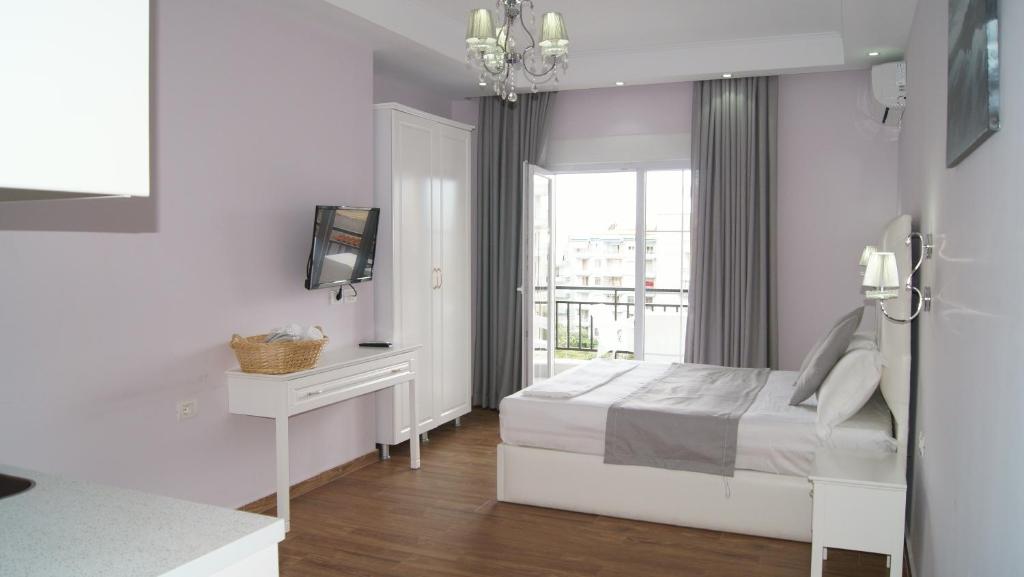 a white bedroom with a bed and a window at Apartments Flower Residence in Sarandë