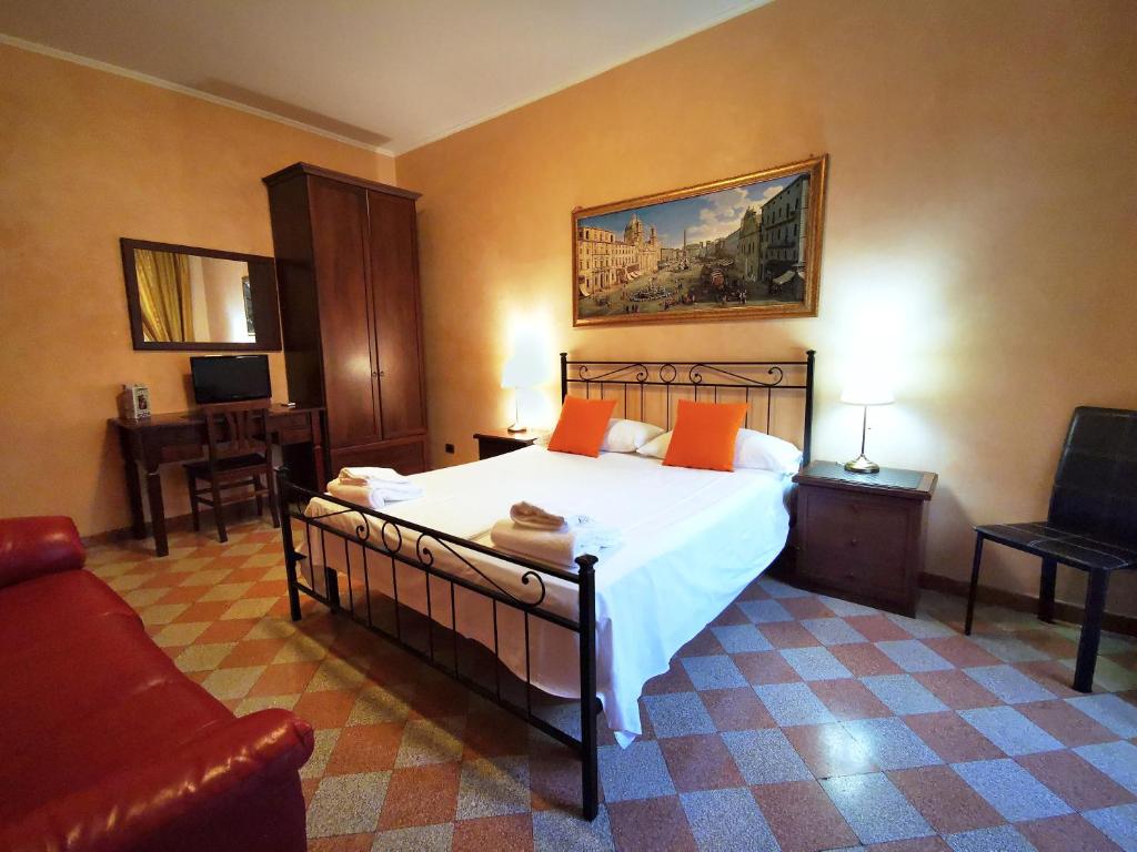 ein Schlafzimmer mit einem Bett mit orangefarbenen Kissen und einem Sofa in der Unterkunft Maestoso Appartamento Turistico in Rom