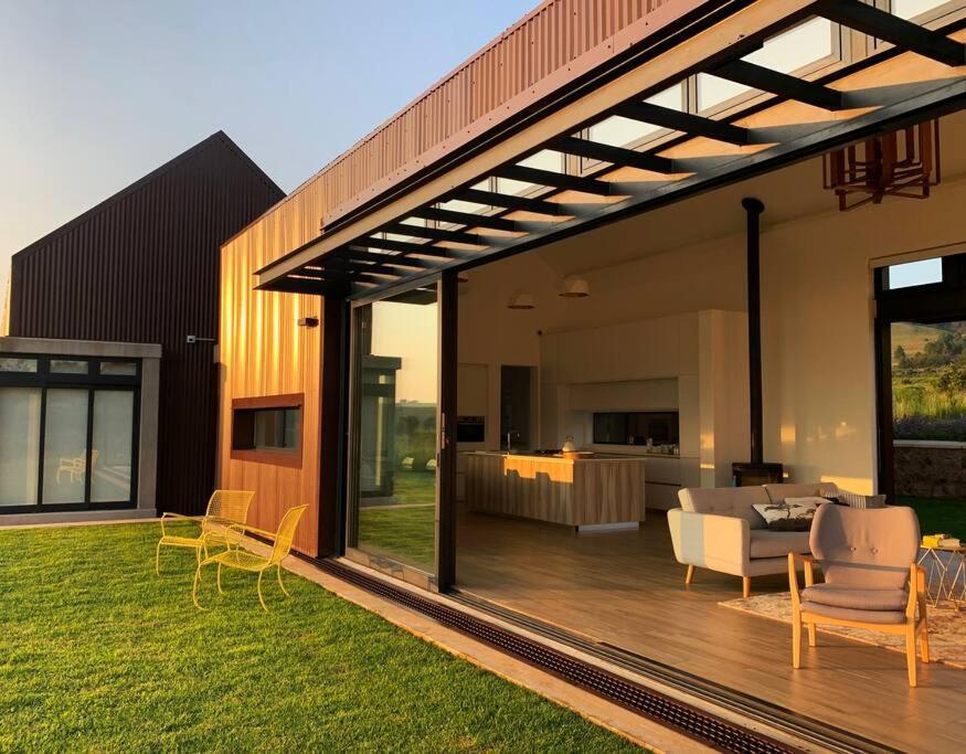 a modern house with a deck with a living room at Walkersons Estate- Outcrop in Dullstroom