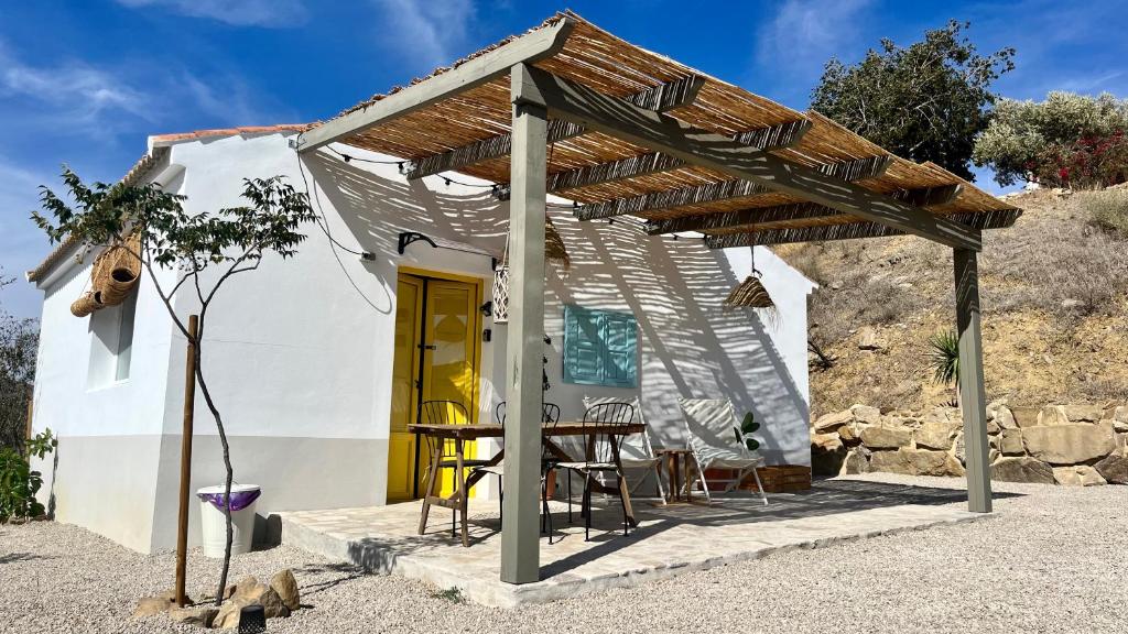 une petite maison blanche avec une table et des chaises dans l'établissement Casita Malacitano, Caminito del Rey, à Valle de Abdalagís
