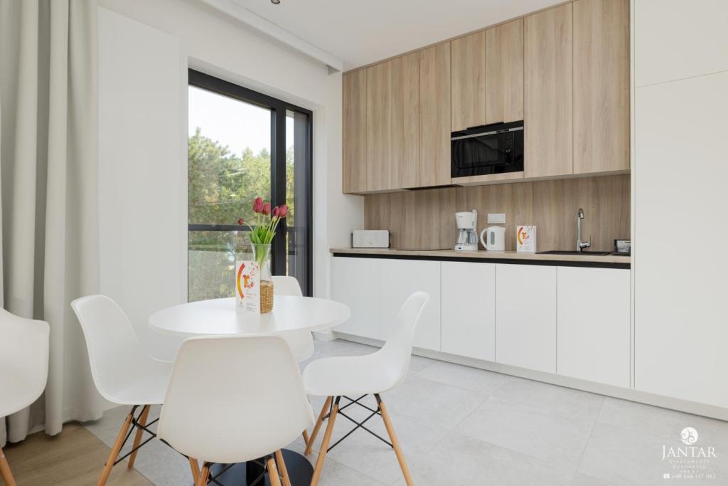 uma cozinha com uma mesa branca e cadeiras brancas em Shellter Apartments 117 J - by Jantar Apartamenty em Rogowo