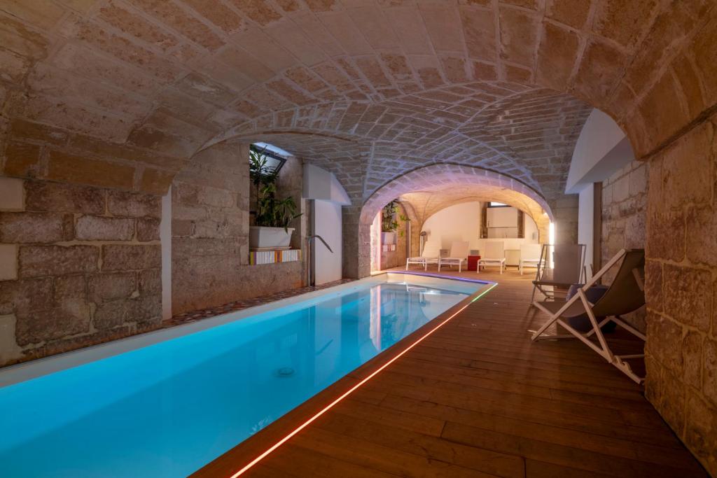 einen Innenpool in einem Gebäude mit einer Steinmauer in der Unterkunft VIANNA SUITES SPA in Lecce