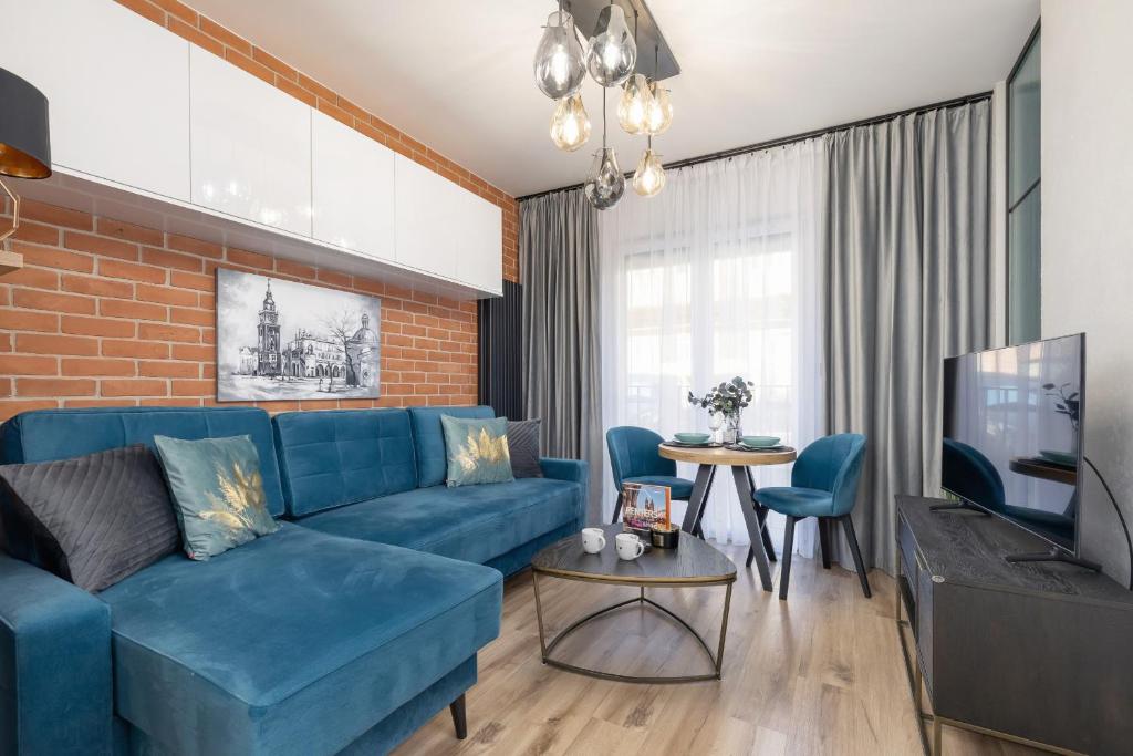 ein Wohnzimmer mit einem blauen Sofa und einem TV in der Unterkunft Lux Kraków Apartment with Parking & AC just 1,5 km from Main Square by Renters Prestige in Krakau
