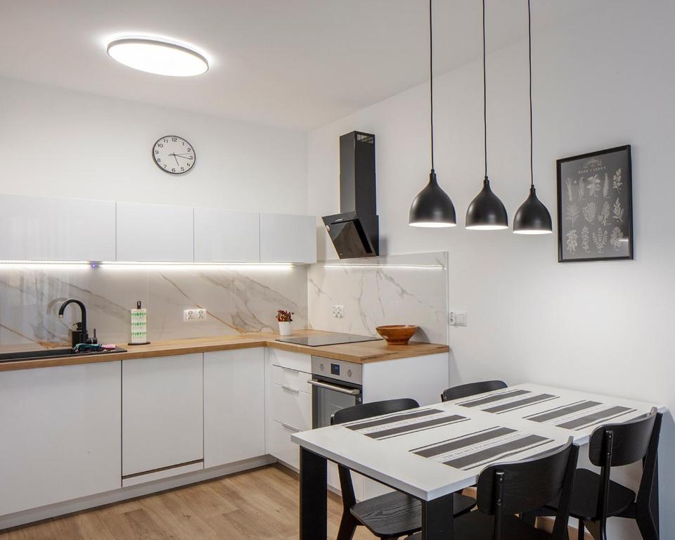 cocina con armarios blancos, mesa y sillas en WOART Apartments en Sosnowiec
