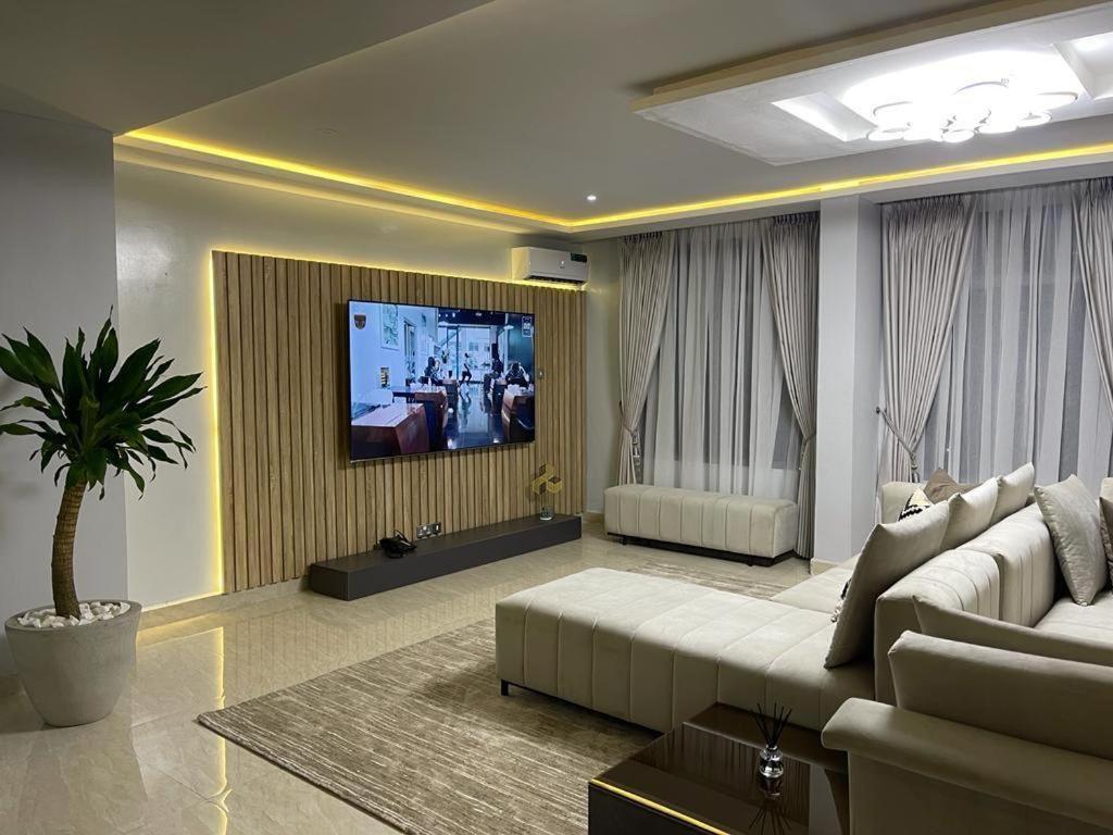 een woonkamer met een bank en een flatscreen-tv bij Dominion Court in Lagos