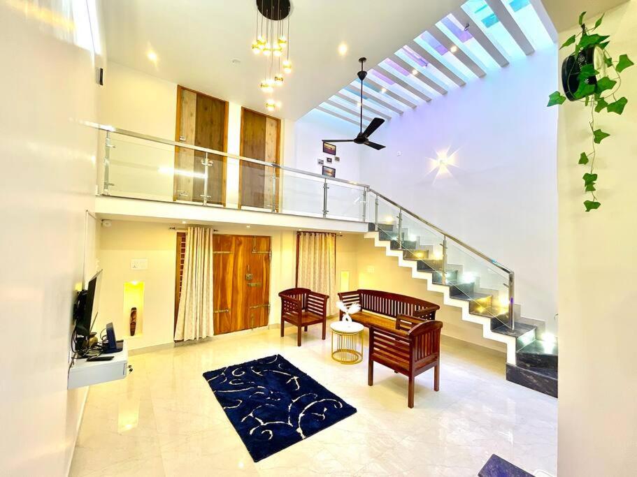 een woonkamer met een trap en een tafel en stoelen bij Villa Porto' Lux beach house', Pondicherry in Pondicherry