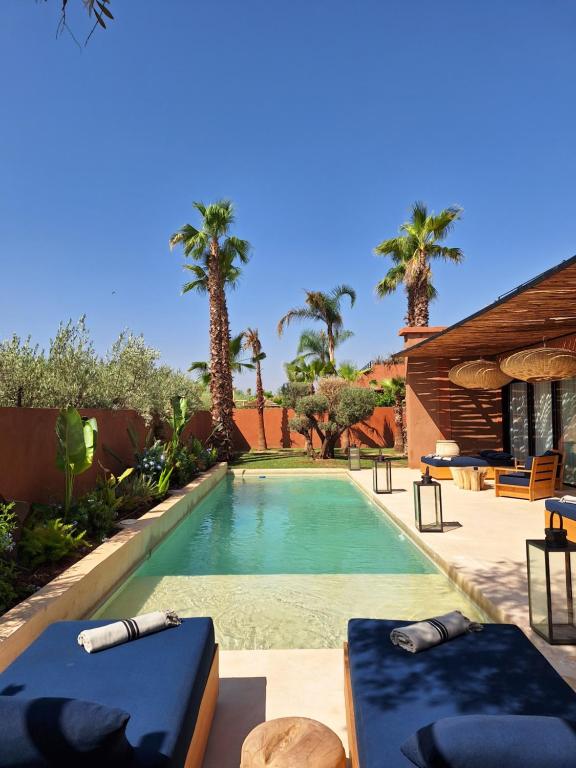 a swimming pool in a backyard with palm trees at Villa M golf Amelkis à proximité in Marrakech
