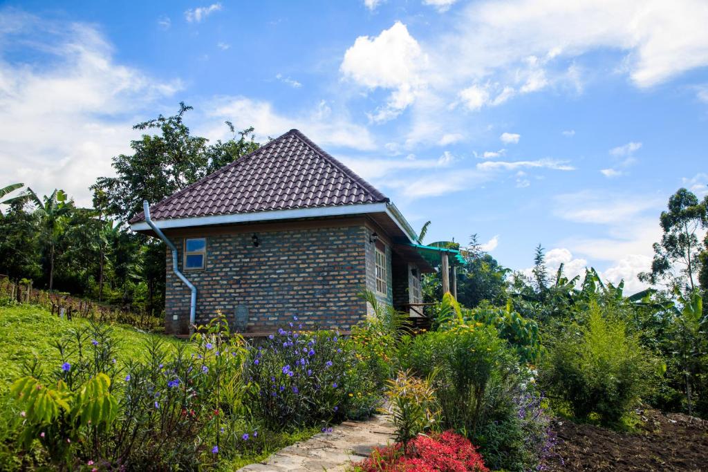 a brick house with a garden in the foreground at Apuuli Safaris and Cottages in Kasusu