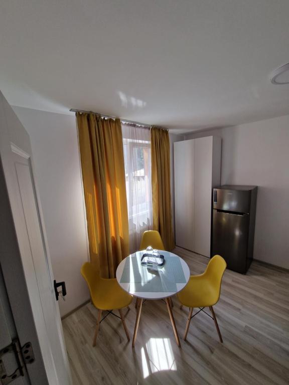 ein kleiner Raum mit Tisch und Stühlen und einem Kühlschrank in der Unterkunft my TinyPlace in Târgu Mureș