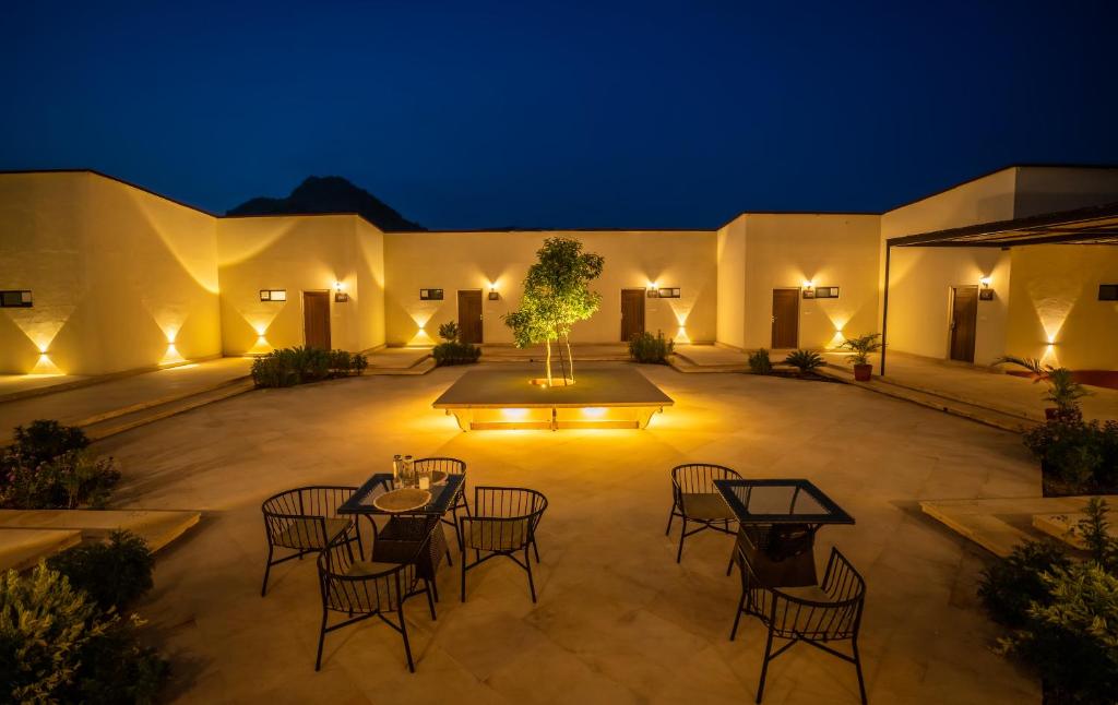 a courtyard with tables and chairs at night at Guldaar - A Luxury Forest Retreat in Tehla