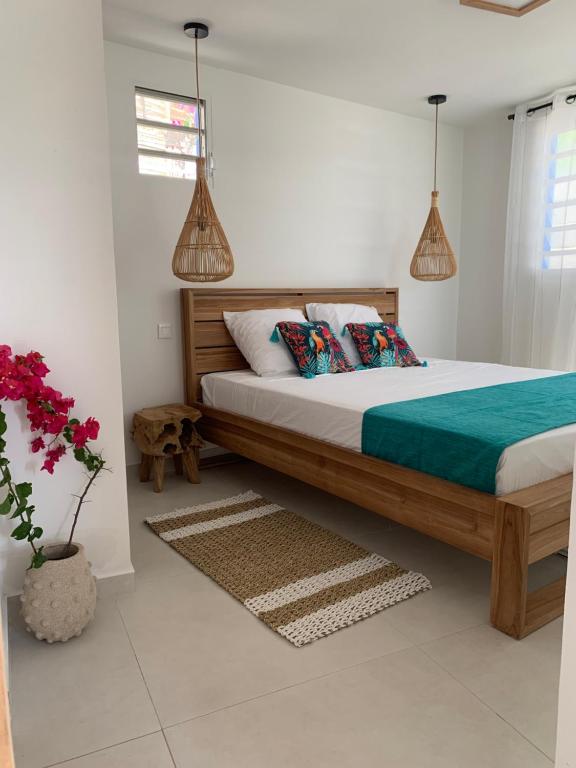 um quarto com uma cama e um vaso com flores em Gite Ti Bali em Deshaies