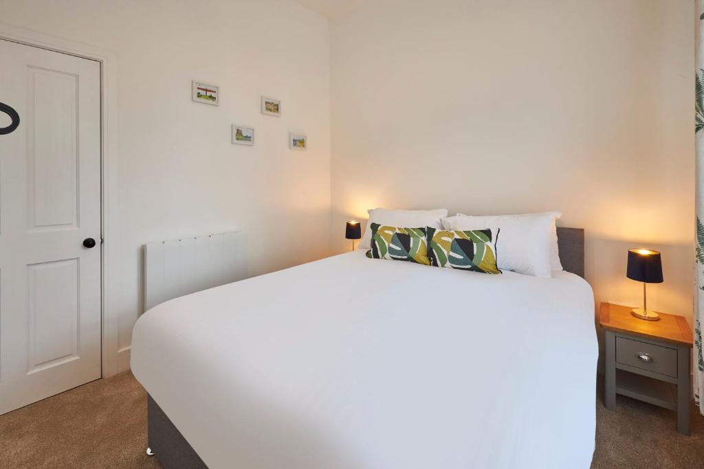una camera bianca con un grande letto bianco con due cuscini di Host & Stay - Main Street Apartments a Seahouses