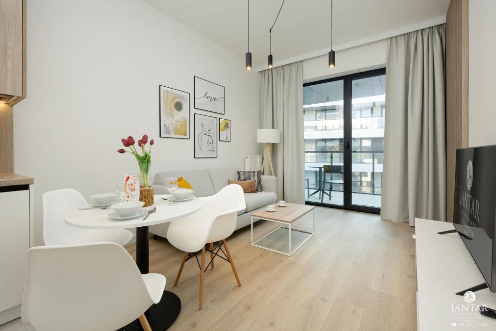 a white living room with a table and chairs at Shellter Apartments 117 H - by Jantar Apartamenty in Rogowo