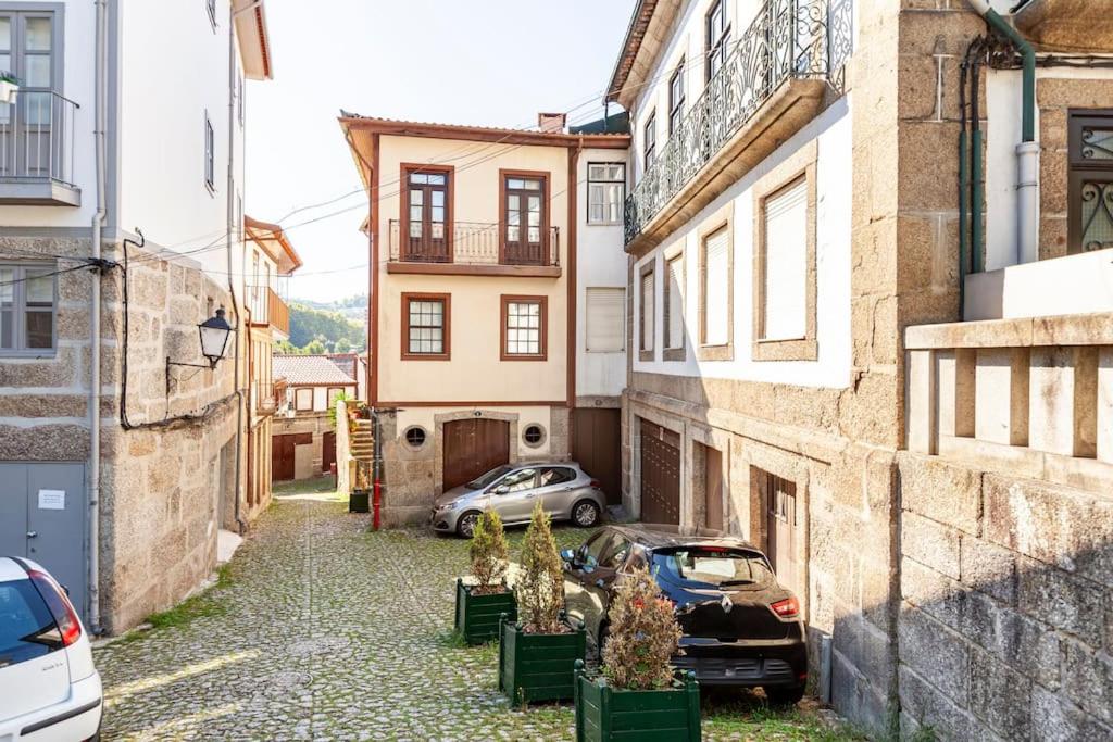 an alley with two cars parked in front of buildings at Casa da Avó Zilda in Guimarães