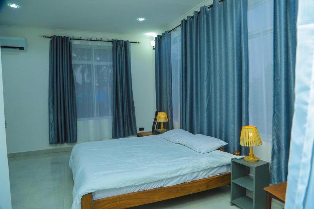 um quarto com uma cama com cortinas azuis e 2 candeeiros em A Gorgeous Condo with a kingsize bed em Dar es Salaam