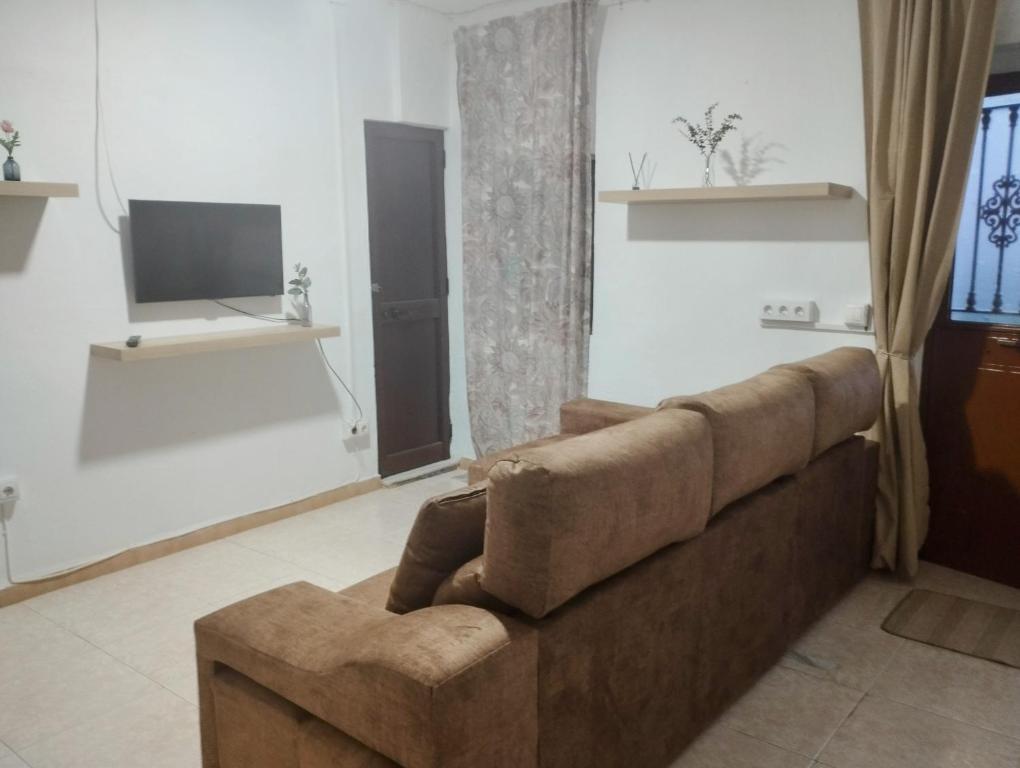 ein Wohnzimmer mit einem braunen Sofa und einem TV in der Unterkunft Casa Duque in Prado del Rey
