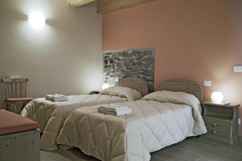 a bedroom with two beds and a painting on the wall at L'Abrì in Pietraporzio