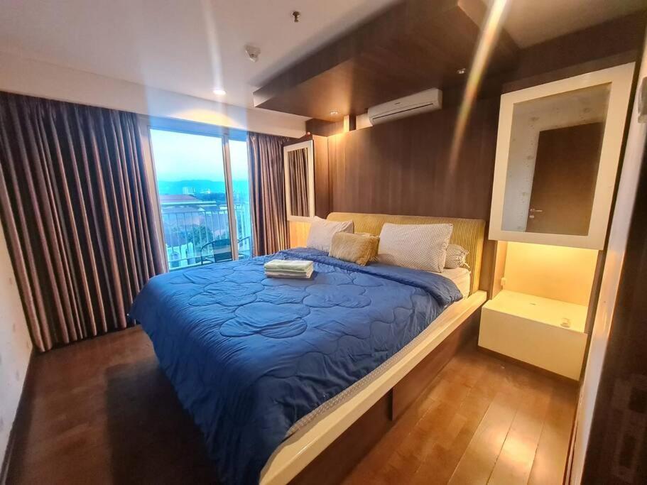 Un dormitorio con una cama azul y una ventana en 2BR El Royale Apartement Braga en Bandung