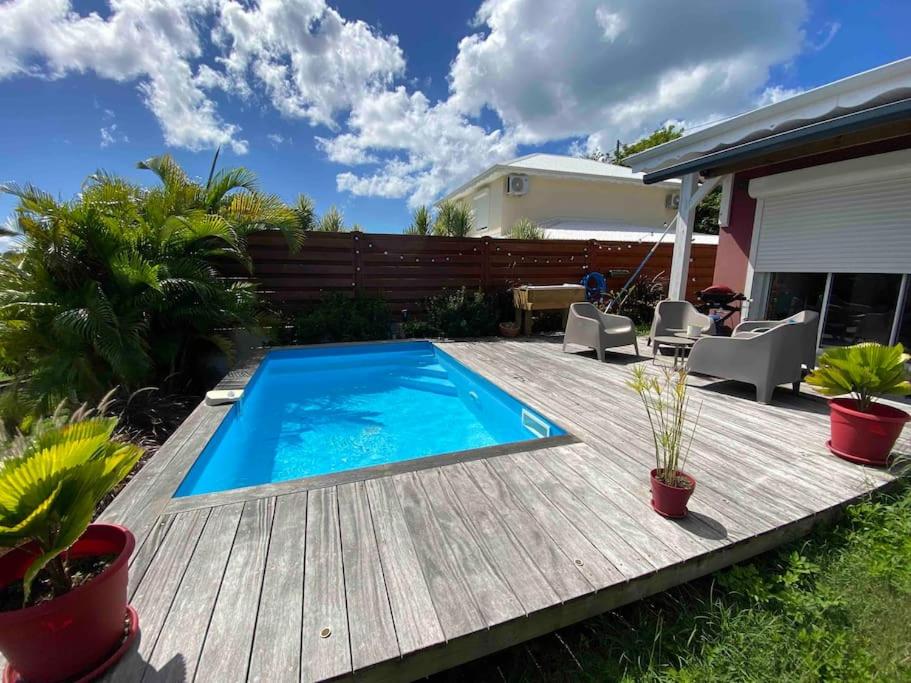 una terraza de madera con piscina en el patio trasero en Villa cosy toute équipée avec piscine, en Le Gosier
