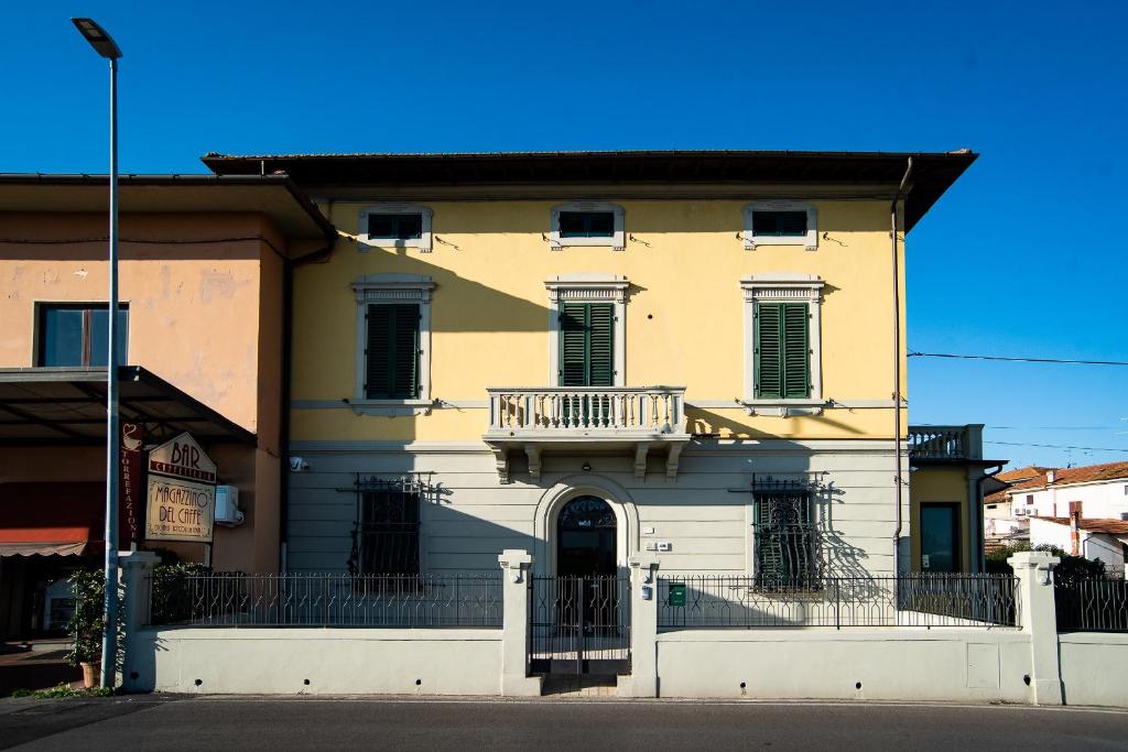 un bâtiment jaune avec un balcon dans une rue dans l'établissement VILLARTE, à Agliana