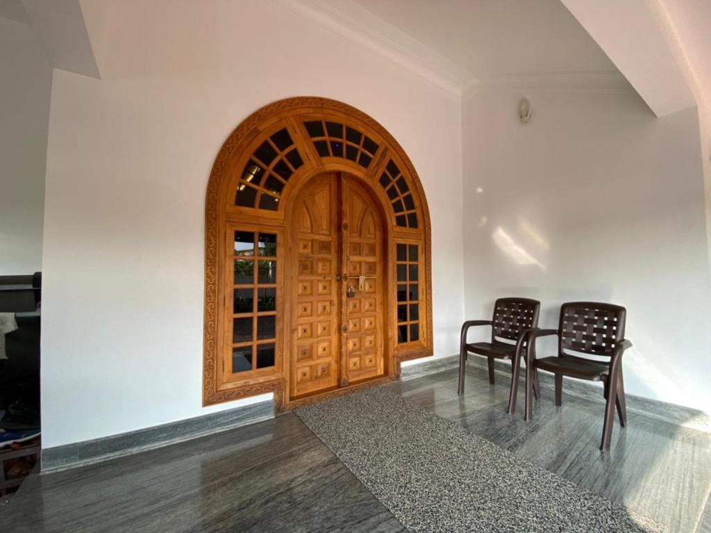 dwa krzesła i drewniane drzwi w pokoju w obiekcie S VILLA w mieście Wayanad