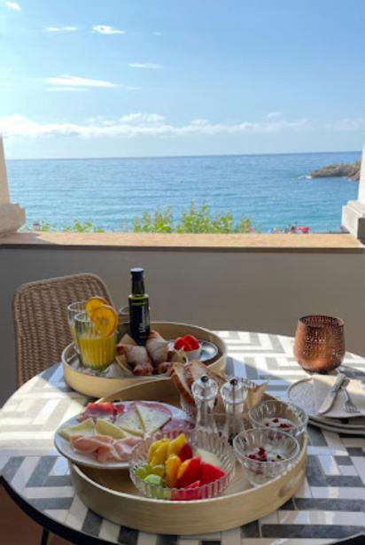 a table with a tray of food and a view of the ocean at Casa Indiana Hotel Boutique in Blanes
