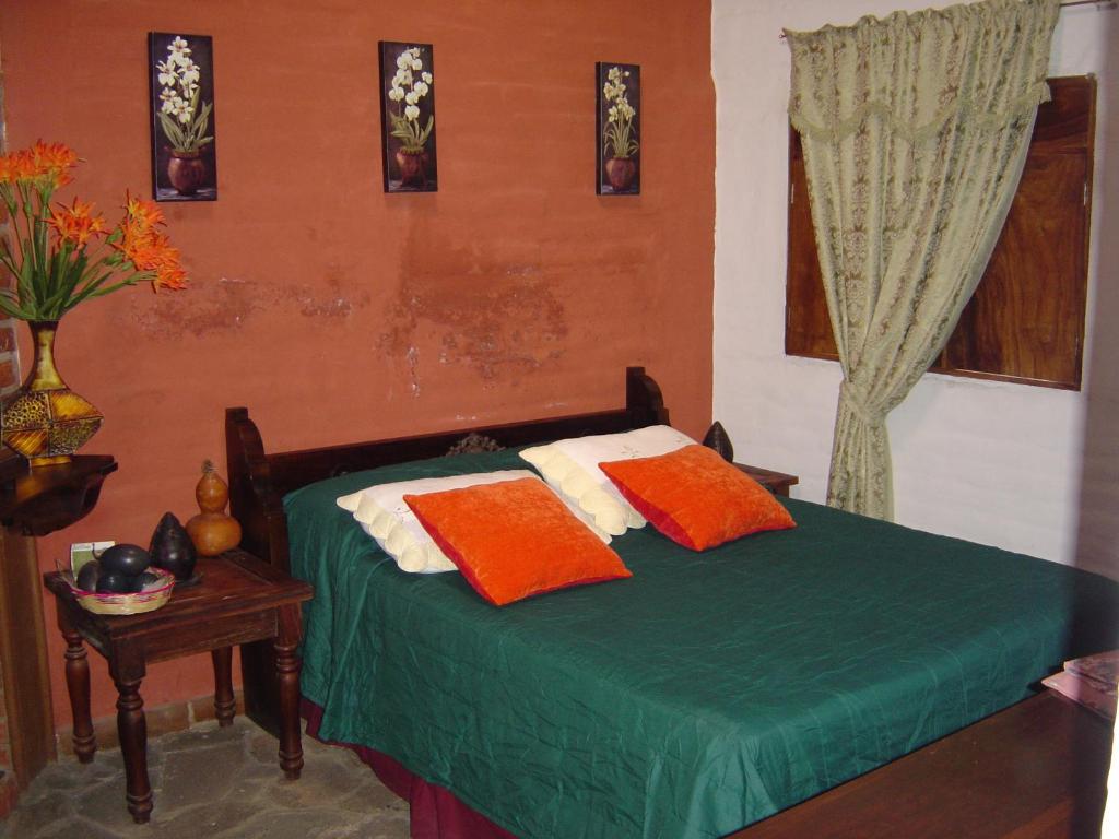 a bedroom with a green bed with orange and white pillows at Hotel Villa Santo Domingo in Concepción de Ataco