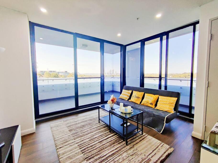 a living room with a couch and a table at Sun-filled Apt w Stunning Open Views of Park&City in Sydney