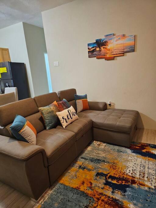 een woonkamer met een bruine bank en een tapijt bij SG Apartment Complex (Apt #1) in Linstead