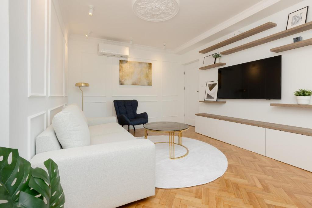 a living room with a white couch and a tv at Apartment in the Centre of Warsaw by Renters in Warsaw